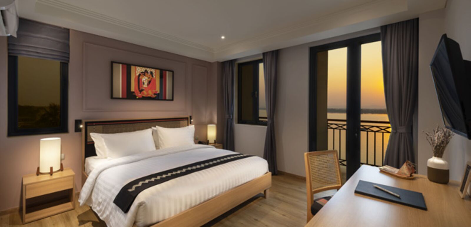 Guest room at sunset, with a balcony and warm bedside lamps